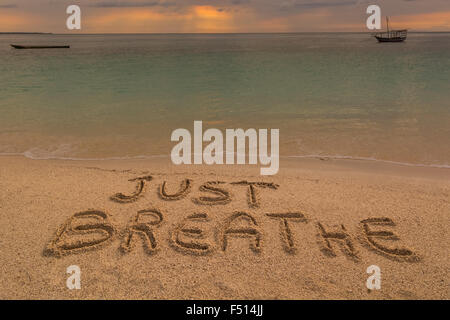 Nella foto una spiaggia al tramonto con le parole sulla sabbia 'appena respirare". Foto Stock