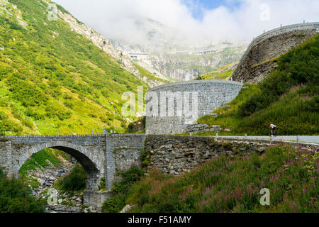 La vecchia strada tremola a gotthardpass, passo del San Gottardo, è passato un ponte e windig fino a verde pendio di montagna Foto Stock