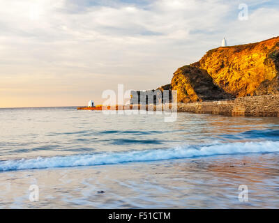Luce della Sera sul molo e scogliere a Portreath Cornwall Inghilterra UK Europa Foto Stock