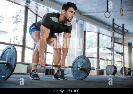 Athlet indossare pantaloncini blu e nero t-shirt sollevamento di grandi barbell Foto Stock