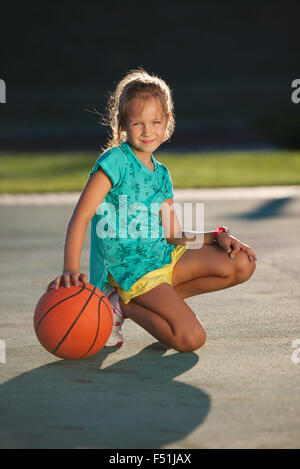 Poco carino ragazza giocare a basket all'aperto Foto Stock