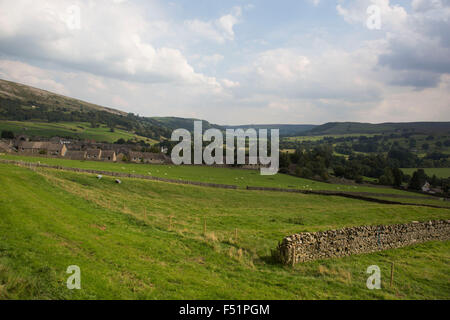 Vista da Swaledale Reeth attraverso fellside campi di terreni agricoli e muri in pietra a secco. Yorkshire, Inghilterra, Regno Unito. Questa è una zona agricola dove la vita rurale e il paesaggio è al centro della vita in questa provincia. Swaledale corre ampiamente da ovest a est. A sud e a est della cresta di un certo numero di piccoli dales. Swaledale è un tipico calcare Yorkshire dale, con la sua stretta valle-fondo stradale, verdi prati e campi fellside, bianco gli ovini e i muri in pietra a secco sul ghiacciaio a valle formata i lati. Foto Stock