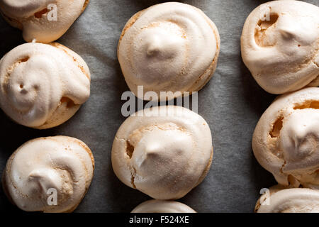 Bianco cotto meringhe pila sul vassoio da forno Foto Stock