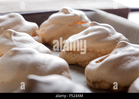 Bianco cotto meringhe pila sul vassoio da forno Foto Stock