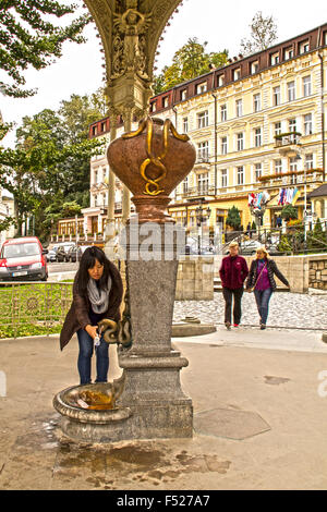 Karlovy Vary, Repubblica Ceca - 22 Settembre 2015: donna asiatica prendere acqua in porcellana speciale cappuccio dalla sorgente minerale 'Snake". Foto Stock