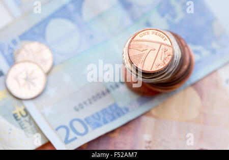 British un penny moneta su una pila di monete e 20 Euro nota Foto Stock