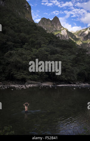 Un turista balneazioni in fiume Urubamba accanto alla montagna dove la città di Machu Picchu è Foto Stock