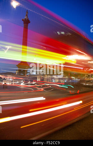 Trafalgar Square red London bus di notte con luci motion blur Nelson la colonna del background in Londra England Regno Unito Foto Stock