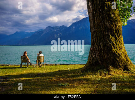 Un giovane si rilassa dal Lago di Ginevra in estate accanto ad un grande albero. Il lago di Ginevra, Svizzera. Foto Stock