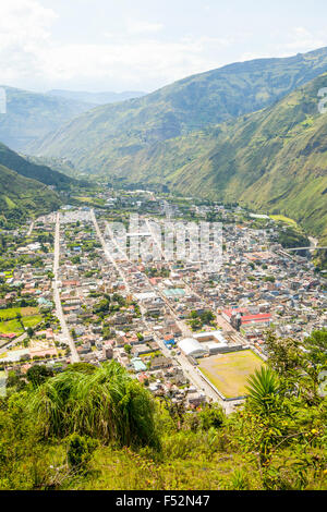 Una vista elevata e ad ampio angolo di una città densamente costruita, annidata in una stretta valle circondata da ripide e verdi montagne. La città presenta una struttura stradale a griglia con numerosi edifici bassi di Foto Stock
