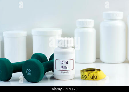 Dieta bianco pillola contenitore con pesi e nastro di misurazione. Foto Stock