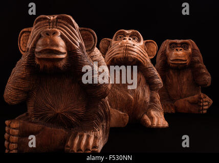 Tre Scimmie sagge. Statuine di legno su uno sfondo nero. Foto Stock