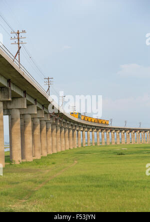 Il treno sulla linea ferroviaria trasversale del campo di erba prato di Pasuk diga sul fiume in estate, Lopburi, Thailandia Foto Stock
