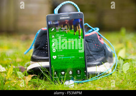 Londra, Regno Unito. Un Samsung smartphone che mostra la sua salute app contro un paio di scarpe da corsa. Foto Stock