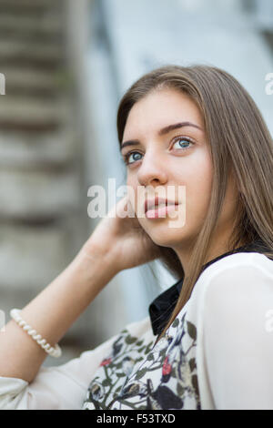 Giovane studente hipster bambina guarda dritto. Ritratto di ragazza carina con capelli lunghi marrone Foto Stock