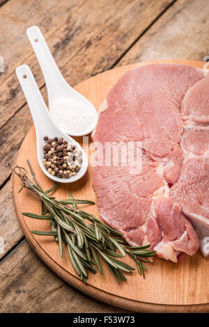 Bistecca con rosmarino e condire su sfondo di legno. Carne di manzo crudo close up immagine Foto Stock