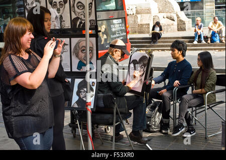 I turisti avente caricatura ritratti eseguiti dall'artista sulla Rambla di Barcellona Catalonia Spagna ES Foto Stock