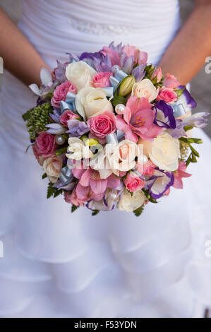 Bouquet rotondo con rose bianche, viola e rosa fresia e perle nelle mani della sposa Foto Stock