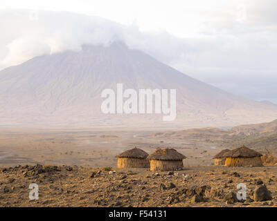 Villaggio masai di fronte all'Ol Doinyo Lengai nella Regione di Arusha, Tanzania Africa. Foto Stock