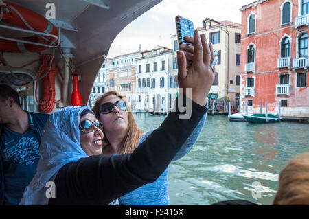 Due donne prendono un telefono selfie foto della fotocamera su un vaporetto sul Canal Grande a Venezia, Italia Foto Stock