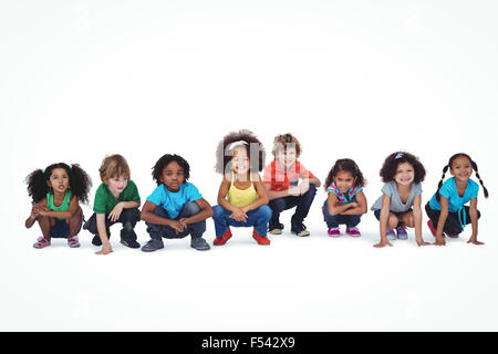 Una fila di bambini accovacciato insieme Foto Stock