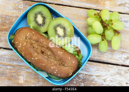 Scuola di sano pranzo scatola contenente pane di segale sandwich, kiwi e uva Foto Stock