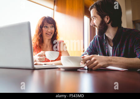 Gli studenti in chat con il cafe utilizzando laptop Foto Stock