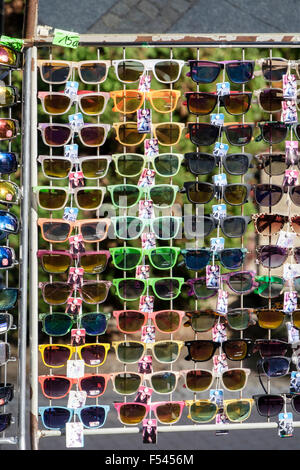 Un sacco di nuove paia di occhiali da sole con cornici colorate per la vendita su un rack in un mercato di strada in stallo. Europa Foto Stock