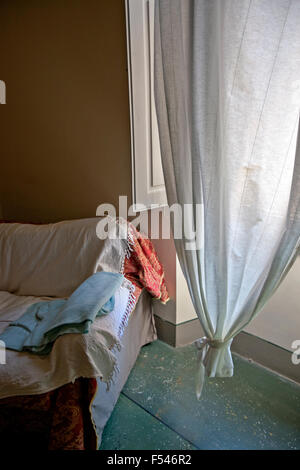 Legato tenda bianca nella finestra accanto alla vecchia sedia con pavimento in marmo e otturatore Foto Stock