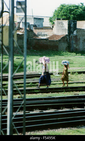 Donna e bambino che trasportano gli effetti personali accanto ad una linea ferroviaria in India - 1992 Foto Stock