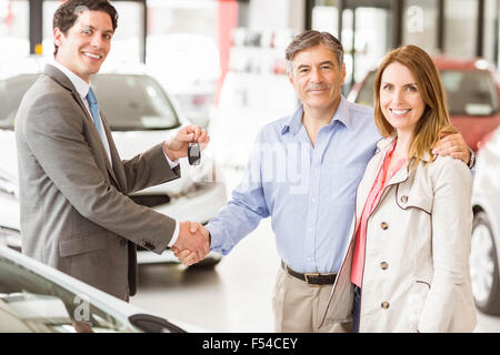 Venditore dando chiave auto per un paio Foto Stock