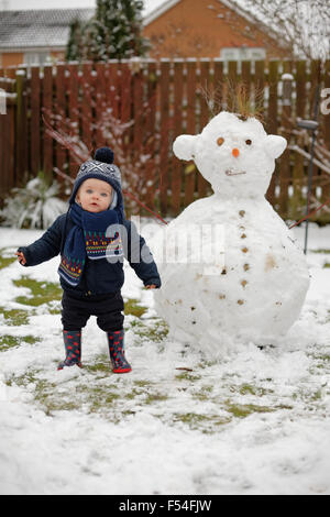 Il Toddler giocando con il pupazzo di neve in giardino durante il periodo invernale Foto Stock