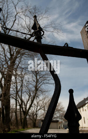 Piegate recinzione in ferro post con alberi e cielo in background. Foto Stock