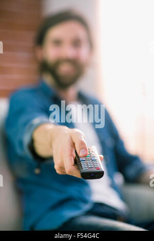 Uomo informale di guardare la TV sul divano di casa Foto Stock