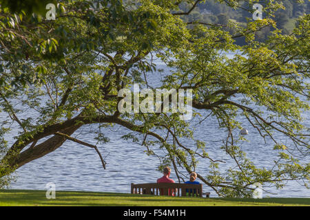 Coppia seduta su una panchina guardando il lago Windremere in Ambleside Cumbria, Foto Stock