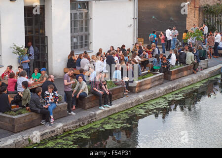 I giovani seduti e bere fuori gabbia pub birreria a Hackney, Londra England Regno Unito Regno Unito Foto Stock