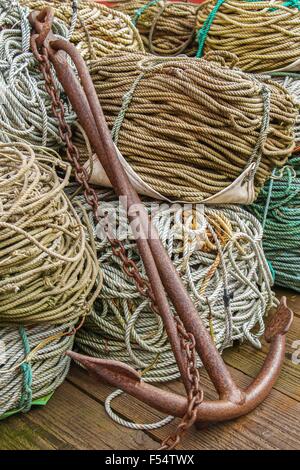 L'immagine verticale di un elemento di ancoraggio con funi su pavimento di legno. Anchor è arrugginita e ha una catena attaccata a sé stessa Foto Stock