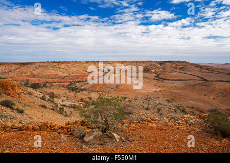 Australian Outback il paesaggio dalla collina lookout, vetta conica salendo dalla valle orlati con rocky red colline sterili, fiori selvatici, cielo blu Foto Stock