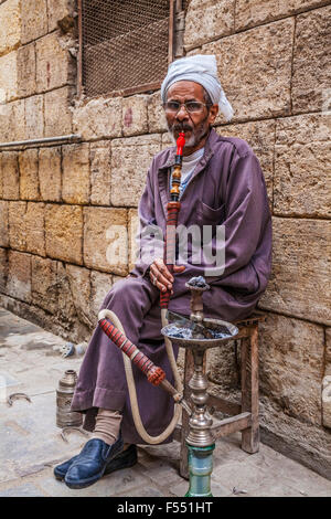 Uomo arabo fuma una tradizionale arabo shisha in Khan el-Khalili souk al Cairo. Foto Stock