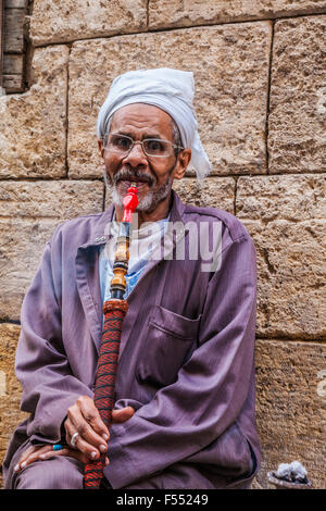 Uomo arabo fuma una tradizionale arabo shisha in Khan el-Khalili souk al Cairo. Foto Stock