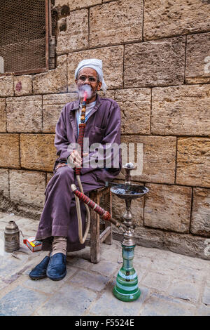 Uomo arabo fuma una tradizionale arabo shisha in Khan el-Khalili souk al Cairo. Foto Stock