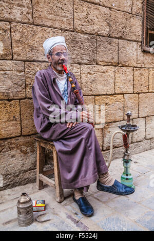 Uomo arabo fuma una tradizionale arabo shisha in Khan el-Khalili souk al Cairo. Foto Stock