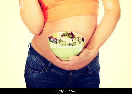 Donna incinta tenendo una ciotola con insalata Foto Stock