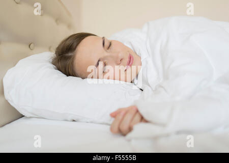Donna sorridente dormire nel letto di casa Foto Stock