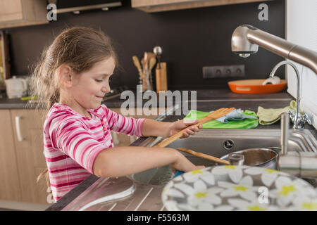 Ragazza sorridente il lavaggio di utensili in cucina a casa Foto Stock