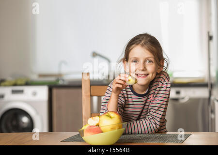 Ritratto di felice ragazza mangiare apple a tavola Foto Stock