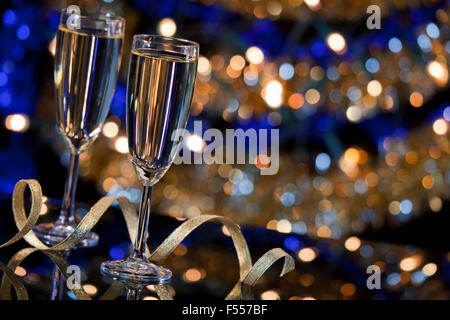 Un Capodanno scena con bicchieri di champagne e le luci di Natale in background. Foto Stock