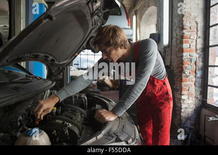 Esaminando meccanico auto a motore al negozio di riparazioni auto Foto Stock