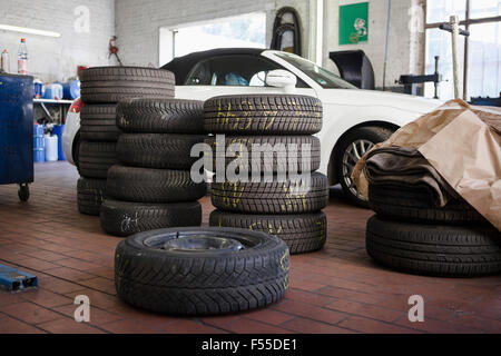 Pneumatici impilati in auto in garage Foto Stock