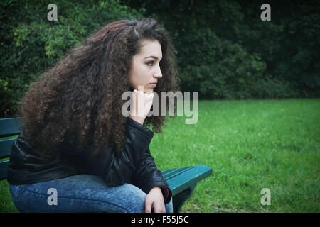 Triste giovane donna seduta sul banco di lavoro Foto Stock